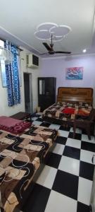 a bedroom with two beds and a checkered floor at Kohli Niwas in Amritsar