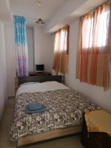 1 dormitorio con 1 cama, TV y ventanas en PERGAMOS APARTMENTS, en Mytilini