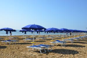 una fila de sillas y sombrillas en una playa en Green Village Eco Resort, en Lignano Sabbiadoro
