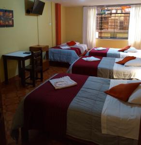 a hotel room with three beds and a table at Hospedaje Del Carmen in Machu Picchu