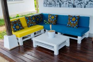 eine blaue und gelbe Couch und ein weißer Tisch in der Unterkunft Long Beach Resort, Nosy Be in Nosy Be