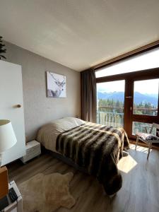 ein Schlafzimmer mit einem Bett und einem großen Fenster in der Unterkunft Duplex Belles Challes in Bourg-Saint-Maurice