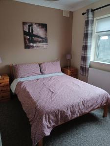 a bedroom with a bed with a purple blanket and a window at Cloonboo Lodge on Wild Atlantic Way Sleeps 12 in Galway