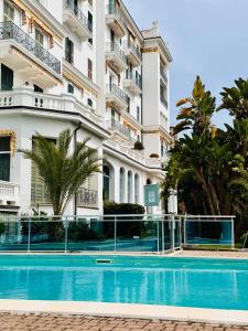 a hotel with a swimming pool in front of a building at Elegant Sea View Retreat in Historic Villa with Pool in Bordighera