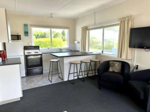 a living room with a kitchen with a stove top oven at Pohara's Seaside Chalet in Pohara