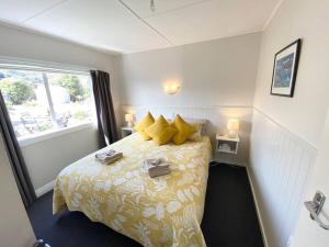 een slaapkamer met een bed met gele kussens en een raam bij Pohara's Seaside Chalet in Pohara