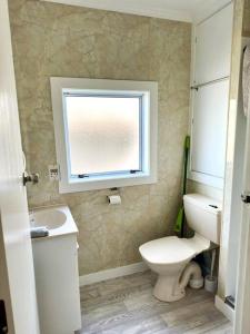 een badkamer met een toilet, een wastafel en een raam bij Pohara's Seaside Chalet in Pohara
