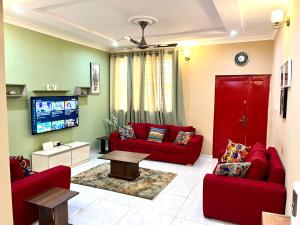 een woonkamer met rode banken en een tv bij Hidden Gem In Oyibi New 2 Luxury Bedroom Apartment in Aburi