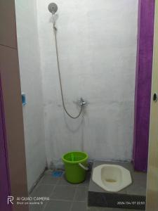 a bathroom with a toilet and a green bucket at D' pamor Homestay in Halangan