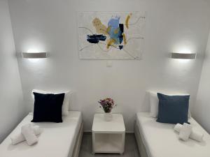 uma sala de estar com duas camas e um vaso de flores em Central Suites Aegina 3 em Egina