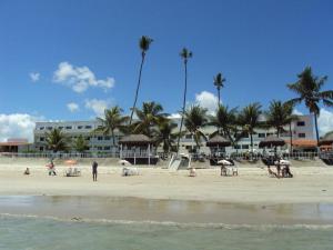 um grupo de pessoas em uma praia com palmeiras em Marinas de Tamandaré 102 em Tamandaré