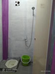 a bathroom with a toilet and a green bucket at D' pamor Homestay in Halangan