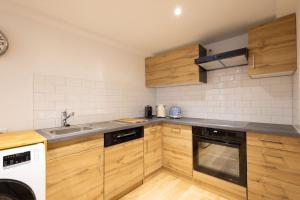 cocina con armarios de madera, fregadero y lavavajillas en Studio-duplex Tower en Visp