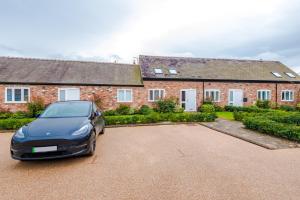 a car parked in front of a brick house at Number 21: A Breathtaking Chester Cottage with Parking in Mollington