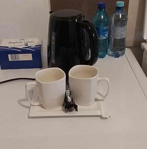 ピテシュティにあるHomeのコーヒーポットの横の皿に座ったコーヒーカップ2杯