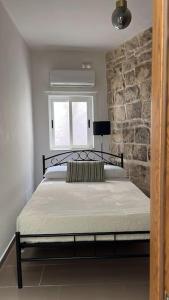 1 dormitorio con 1 cama con pared de piedra en That Little (Old) House en Żurrieq