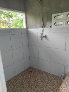 a bathroom with a shower with a tile floor and a window at The Alam Tetebatu Bungalow & Restaurant in Tetebatu