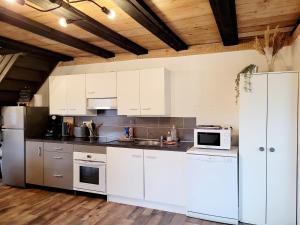 a kitchen with white cabinets and white appliances at Cottage le Ni-La in Fresse-sur-Moselle