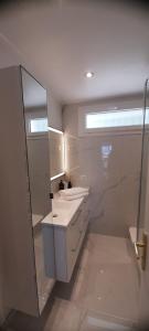 een witte badkamer met een wastafel en een spiegel bij Saint Mandrier 4 pièces vue exceptionnelle - Location à la semaine uniquement in Saint-Mandrier-sur-Mer