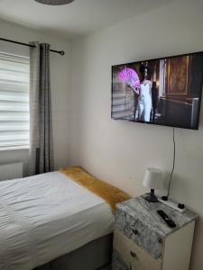 ein Schlafzimmer mit einem Bett und ein Bild einer Frau mit einem Regenschirm in der Unterkunft NB's Cozy Nook in Shevington