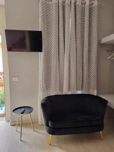 ein schwarzes Sofa im Wohnzimmer mit Vorhang in der Unterkunft Cà Fiamma 2 in Casale Monferrato