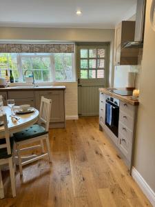a kitchen with a table and a table and chairs at Situated in Stunning Highleigh Village,'BRAMLEY FALL COTTAGE'-Attached Cottage,3 Bedrooms-1 on ground level, SLEEPS 6-2 Bathrooms, 9 mins to Sandy Wittering Beach, 5 mins from Southend Barns, Child friendly,Small Breed Dog Friendly 2 max, Parking-EV Point in Chichester +30 photos