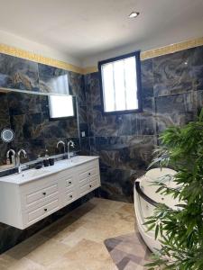 La salle de bains est pourvue d'un lavabo, d'une baignoire et d'une fenêtre. dans l'établissement Villa La Gargouille 300m2 LUX, à Tarascon