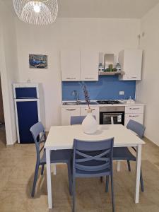 uma cozinha com uma mesa branca e cadeiras azuis em IL BORGO ANTICO - TORRE A MARE em Torre a Mare