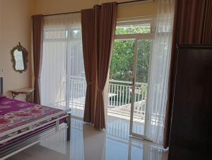 Un dormitorio con una cama y una gran puerta corrediza de vidrio. en Luchis HOME Ijen, en Banyuwangi
