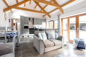 ein Wohnzimmer mit einem Sofa und einer Küche in der Unterkunft Re-imagined Stone Barns in the Country Near the Coast in Padstow