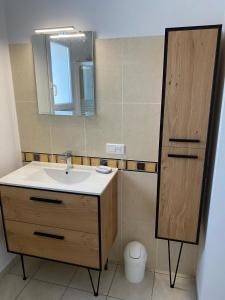 uma casa de banho com um lavatório e um espelho em iledo em La Cotinière