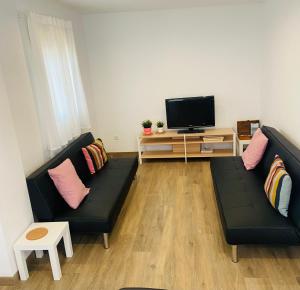 a living room with two black couches and a tv at Casa La via in Camarles