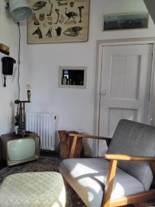 a living room with a tv and a chair at Slapen bij de molenaar in Leerdam +21 photos