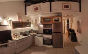 a kitchen with white cabinets and a stainless steel refrigerator at Le duplex panoramic sur Mer et Lido in Sète