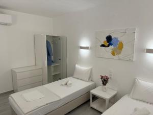 a white bedroom with a bed and a mirror at Central Suites Aegina 4 in Egina