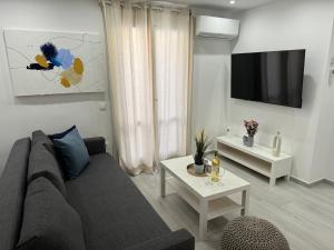 a living room with a couch and a tv at Central Suites Aegina 4 in Egina