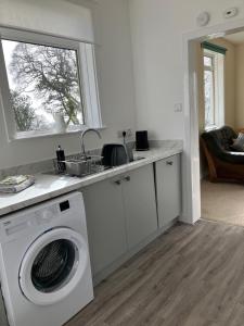 a kitchen with a washing machine and a sink at Dunholm Cottage in Skelmorlie