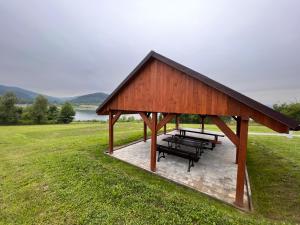a pavilion with benches in a field with a lake at Domki Mucharskie in Mucharz