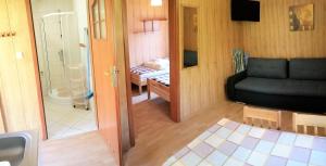 d'un salon avec un canapé noir et d'une salle de bains. dans l'établissement Domki Letniskowe Las Palmas Dąbki, à Dąbki