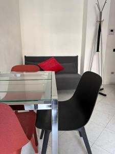 sala de estar con mesa de cristal y sillas rojas en Cozy suite with terrace, en Castellanza