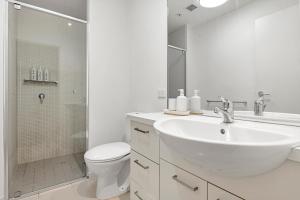 a white bathroom with a sink and a toilet at Sea View, Gym & Pool, 2 bedrooms 2 bathrooms in Melbourne