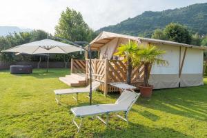 um par de cadeiras e um guarda-sol em frente a uma tenda em Luxury Lodge em Bellagio
