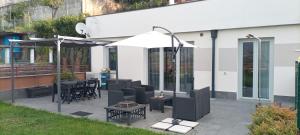 a patio with tables and chairs and an umbrella at Mirasole Holiday House in Leggiuno