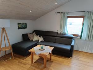 ein Wohnzimmer mit einem schwarzen Sofa und einem Tisch in der Unterkunft Ferienwohnung auf dem Land in Tuntenhausen