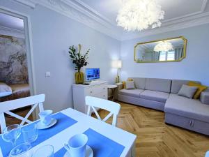 ein Wohnzimmer mit einem Sofa und einem Tisch in der Unterkunft Au Petit Trianon Bleu in Versailles