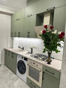 eine Küche mit einem Herd und einer Vase aus Rosen in der Unterkunft Three Palms Guest House in Tbilisi City