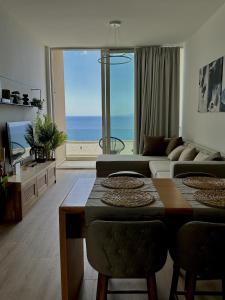 een woonkamer met een tafel en uitzicht op de oceaan bij Sapphire Residence Green Coast in Palasë