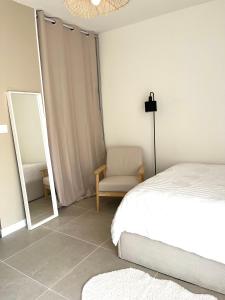 - une chambre avec un lit, une chaise et un miroir dans l'établissement Appartement Balaruc les bains, à Balaruc-les-Bains