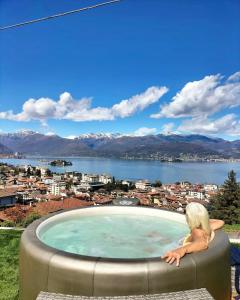 uma mulher sentada numa banheira de hidromassagem com vista para uma cidade em Panorama Loft Apartments em Stresa
