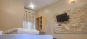 1 dormitorio con TV en una pared de ladrillo en Solace Guest House, en Entebbe